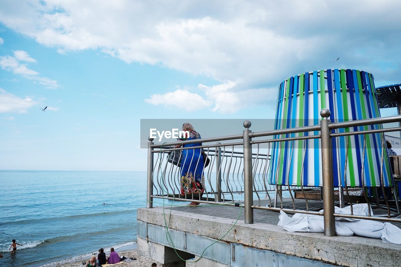 Woman standing by railing against sea