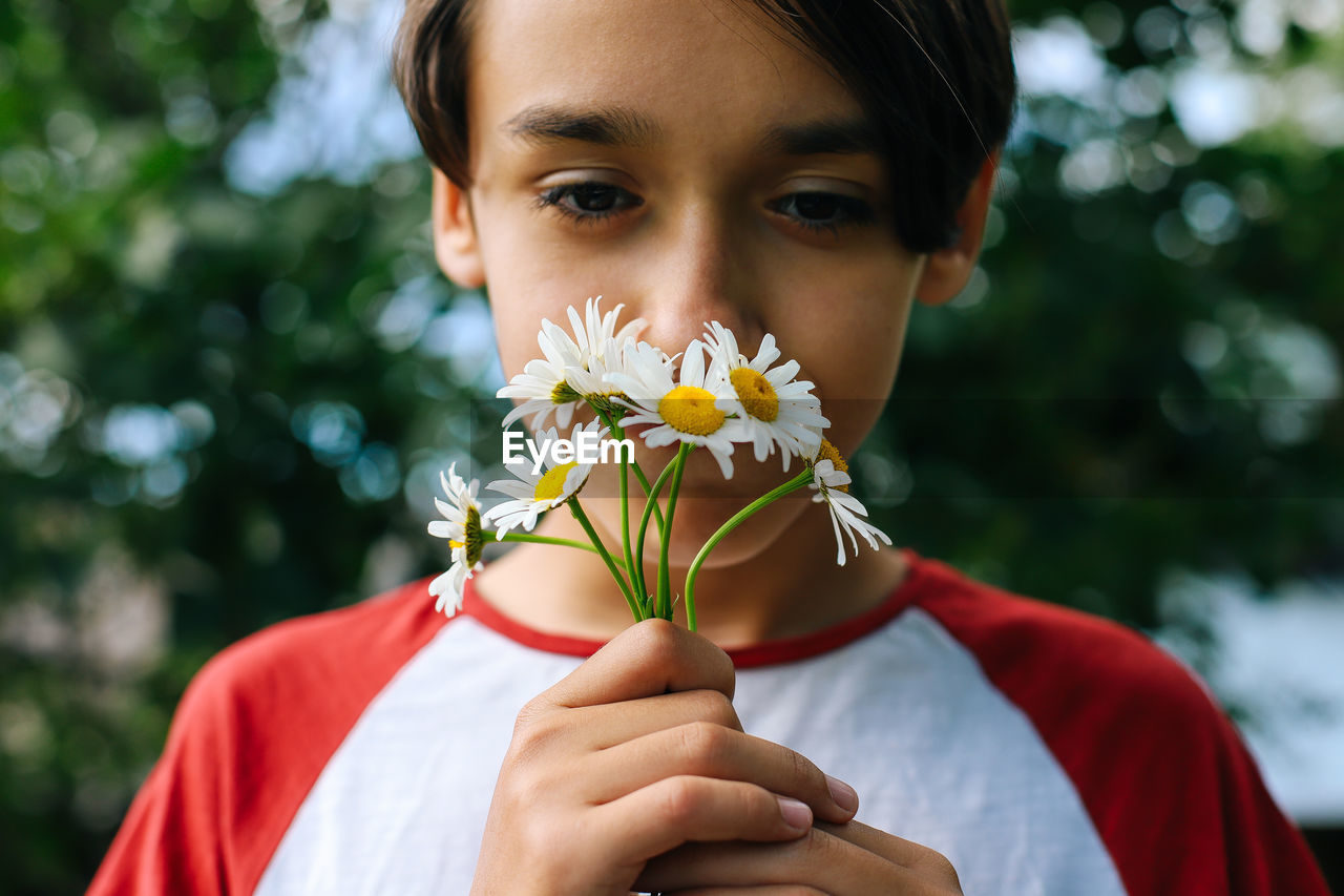 Close-up of boy smelling flowers