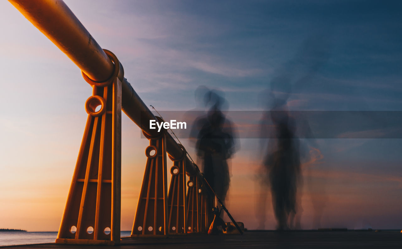 Low angle view of railings on pier against sky during sunset