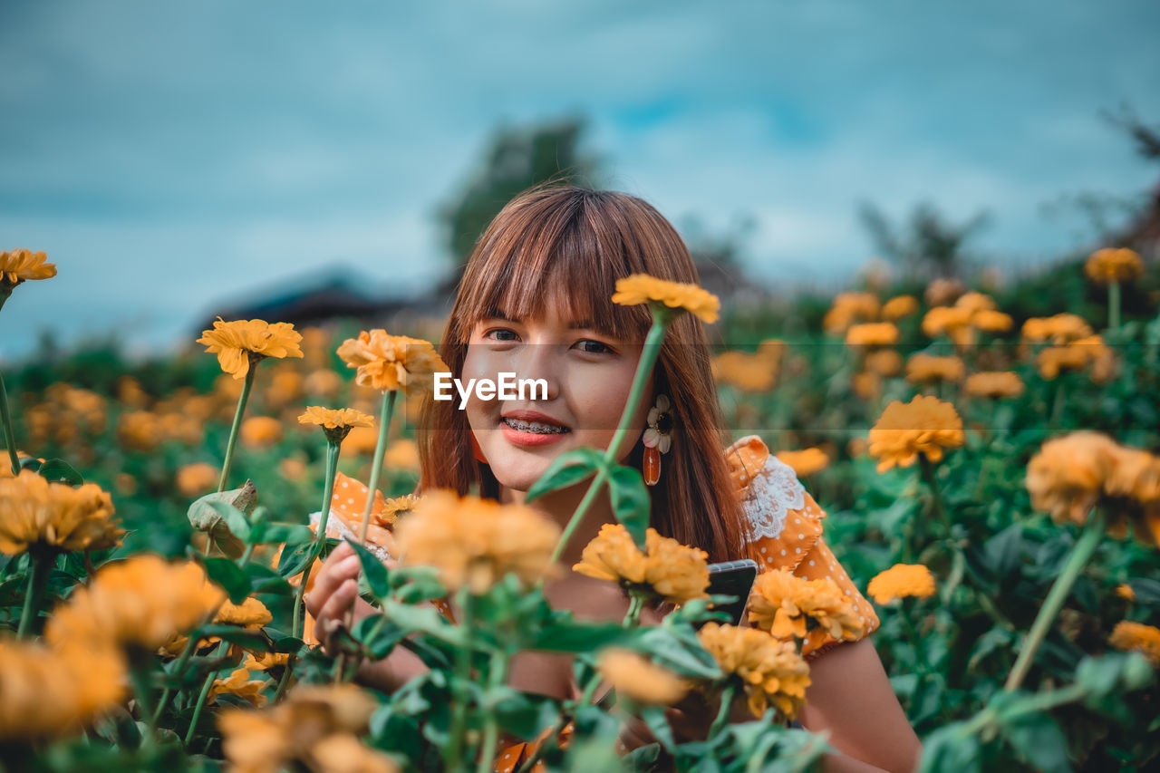 Portrait of smiling woman amidst yellow flowering plants