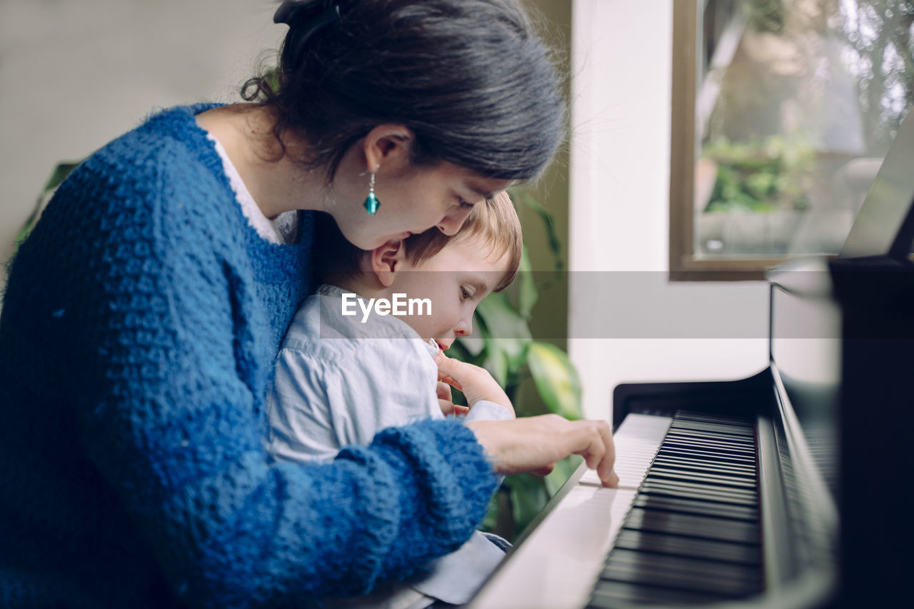 Mother and son playing piano at home