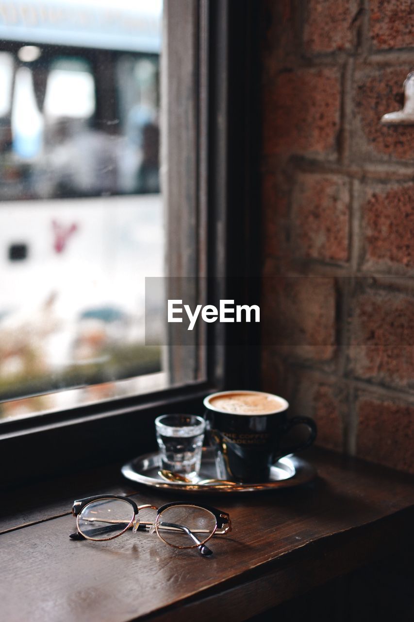 Coffee cup and eyeglasses on table