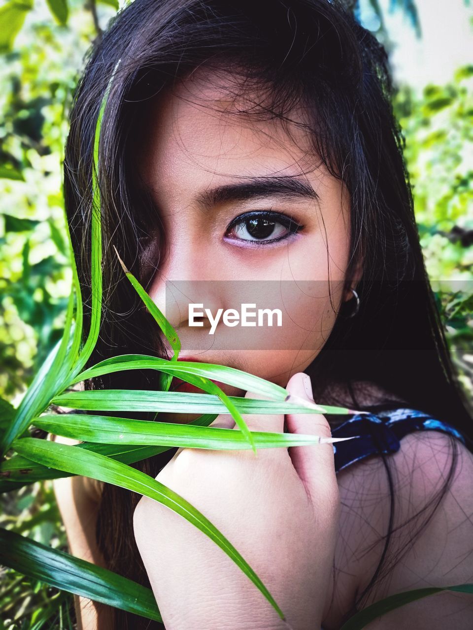 CLOSE-UP PORTRAIT OF GIRL HOLDING LEAF
