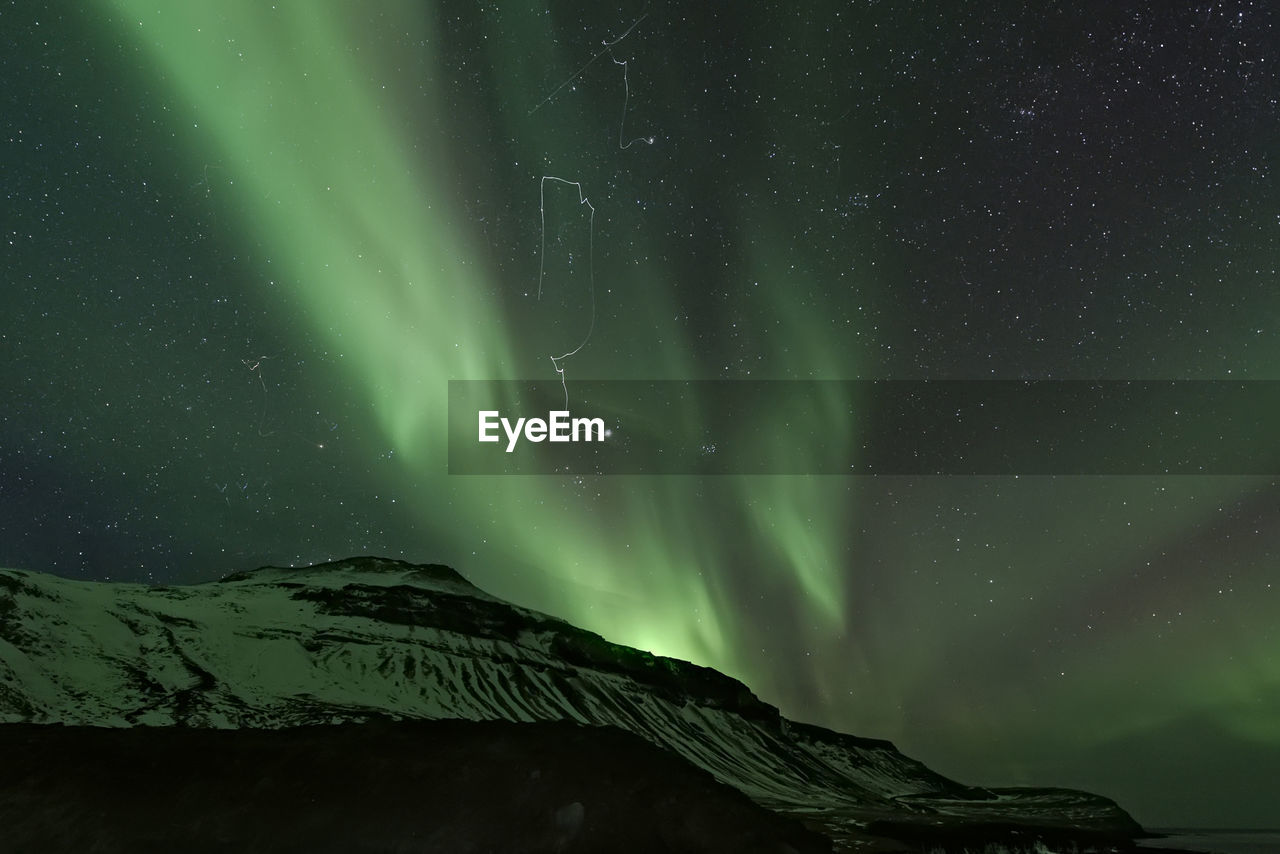 Low angle view of mountain against aurora borealis at night