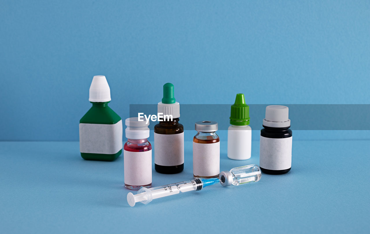 Close-up of syringe with bottles on blue background