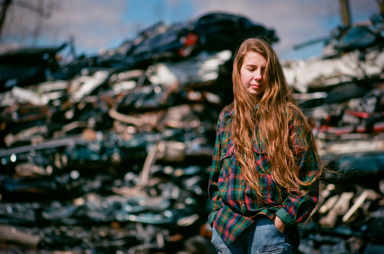 Young woman standing in an auto salvage yard