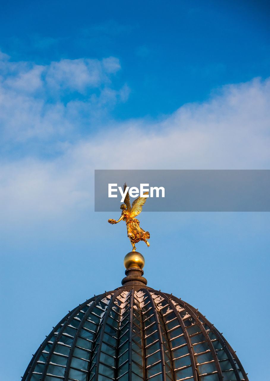 Golden angel statue on dome against sky