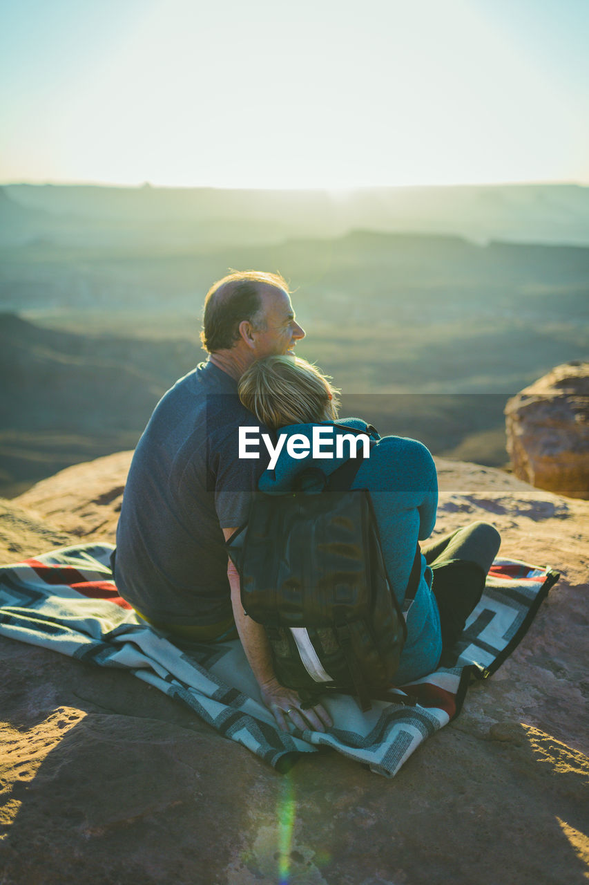 Rear view of romantic couple sitting on mountain at canyonlands national park