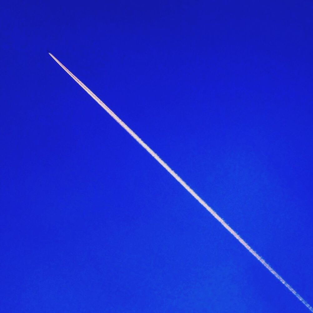 Low angle view of vapor trail in clear blue sky