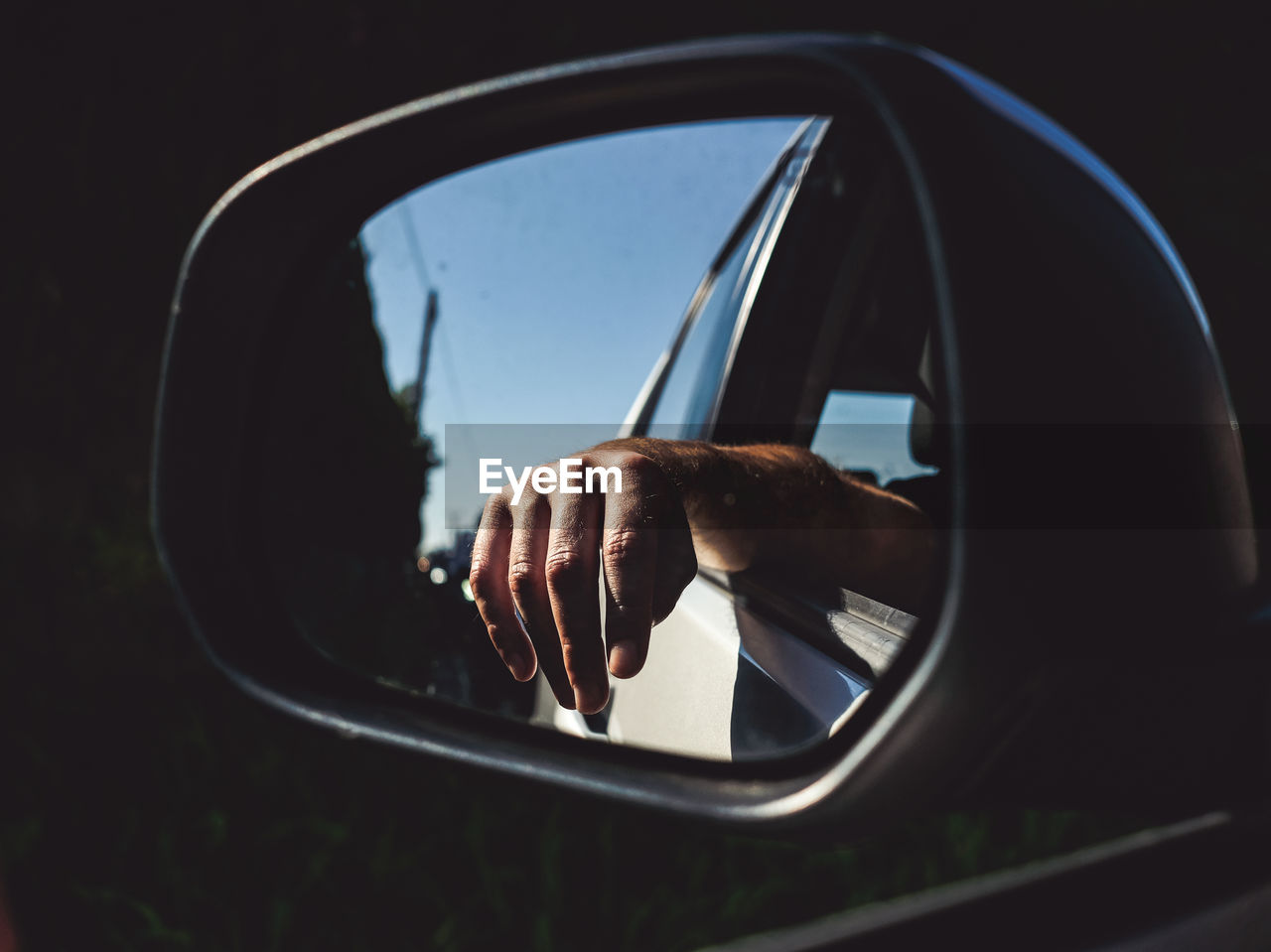 Close-up of hand in side-view mirror of car