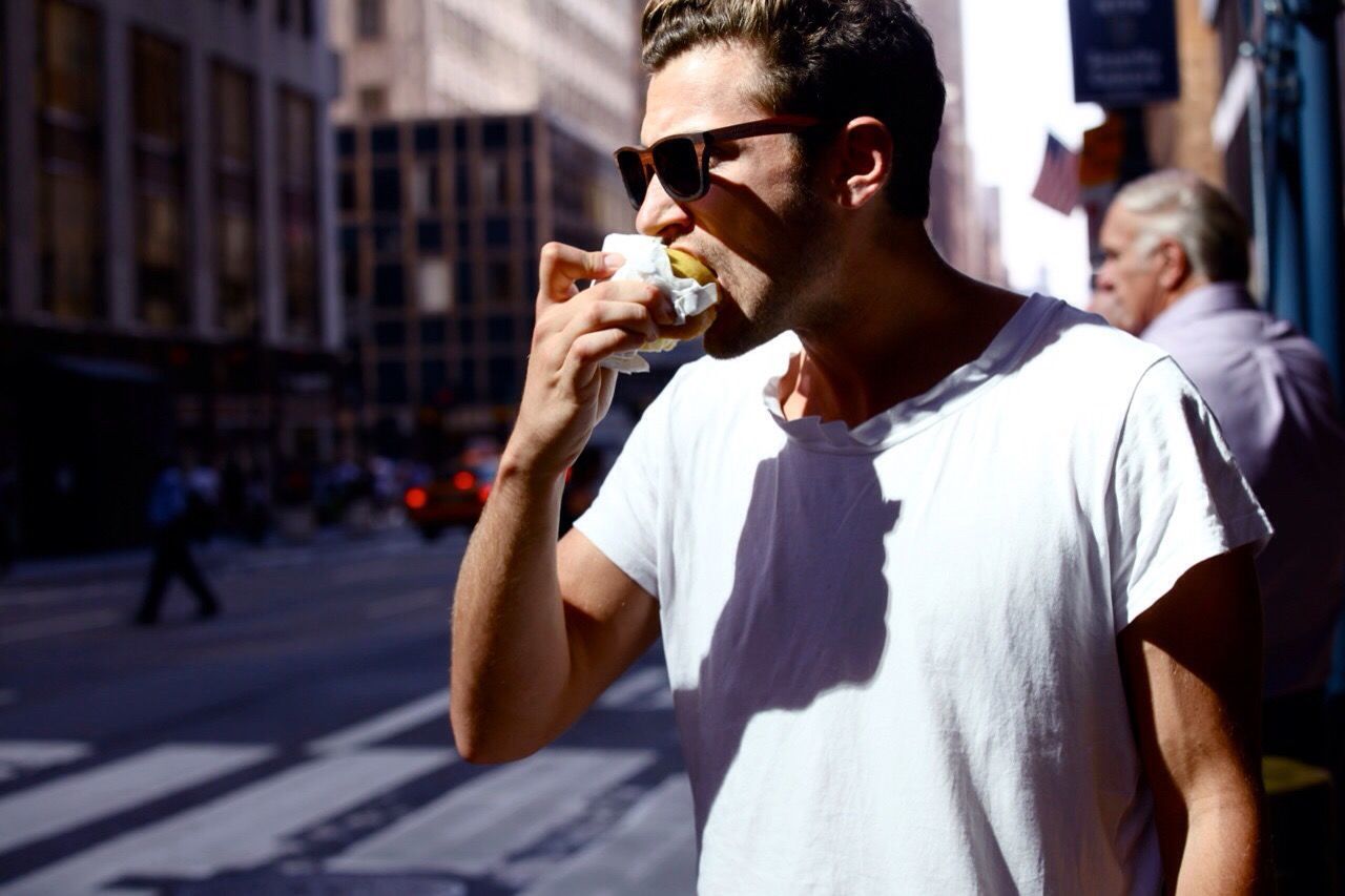 Man eating snack on city street