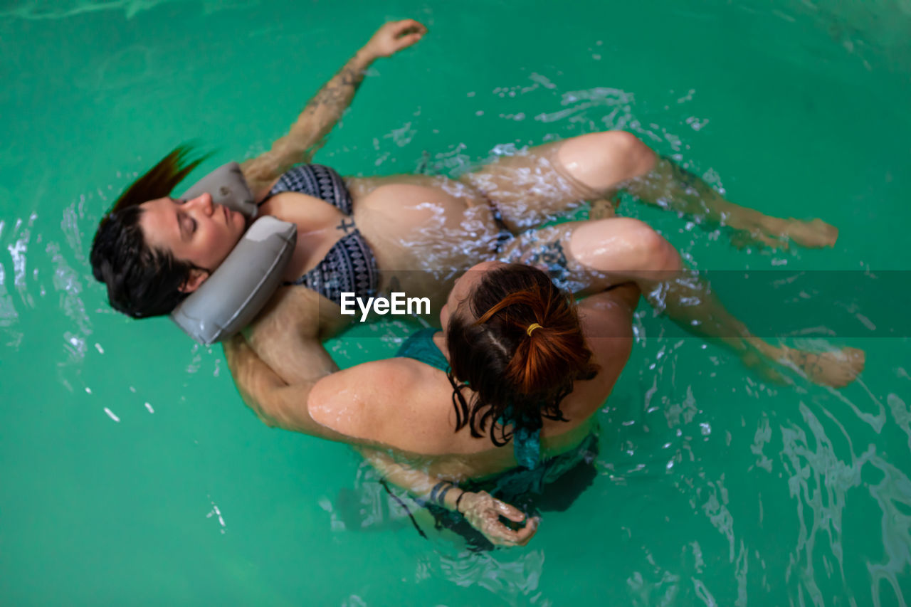 HIGH ANGLE VIEW OF WOMAN SWIMMING IN WATER