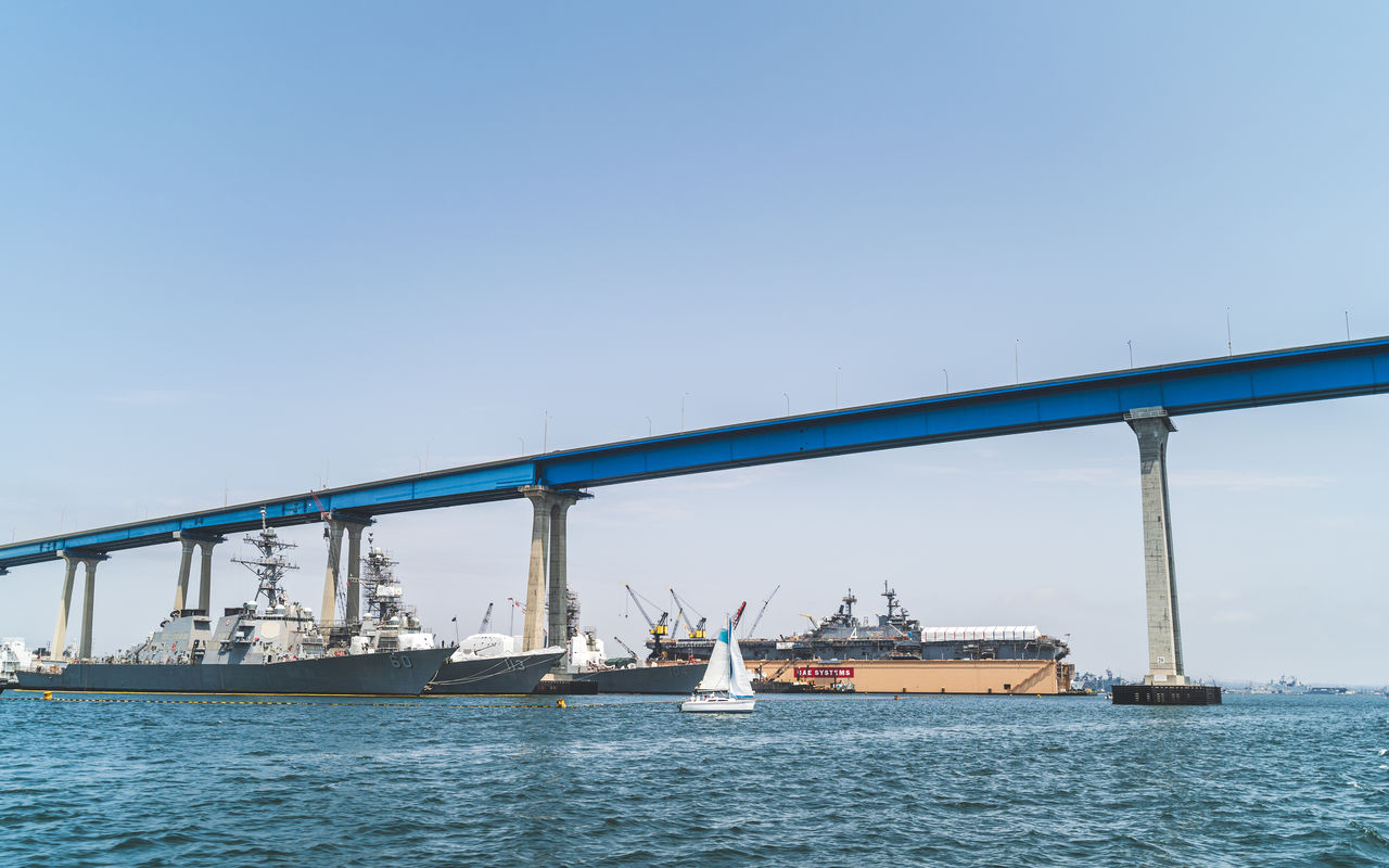 transportation, water, sky, architecture, sea, nautical vessel, mode of transportation, vehicle, built structure, nature, bridge, copy space, clear sky, blue, travel, day, ship, no people, business, freight transportation, shipping, boat, industry, outdoors, travel destinations, sunny, city, waterfront, pier, bay, business finance and industry, watercraft, beauty in nature
