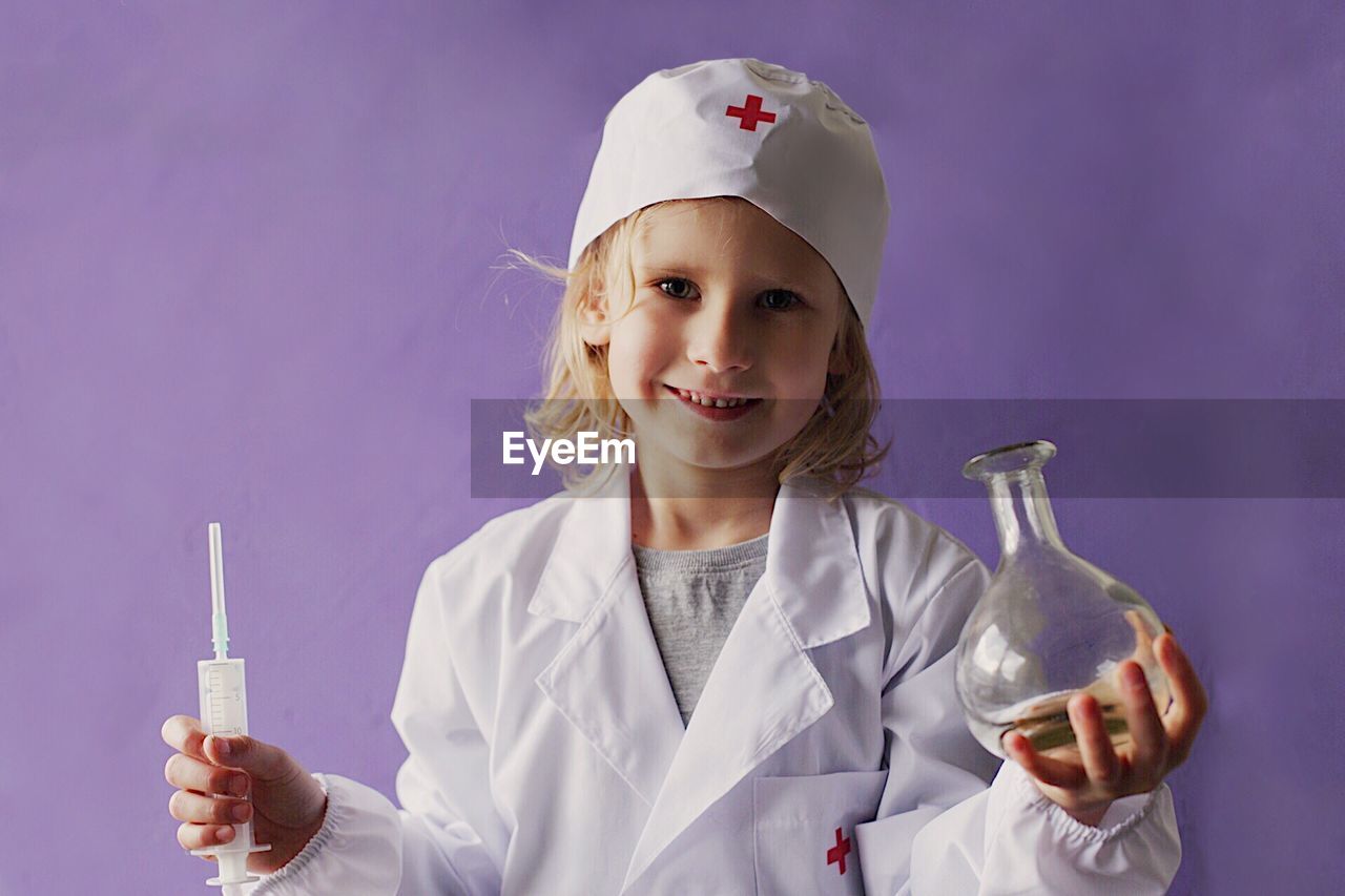 Portrait of smiling girl wearing scrubs holding medical equipment
