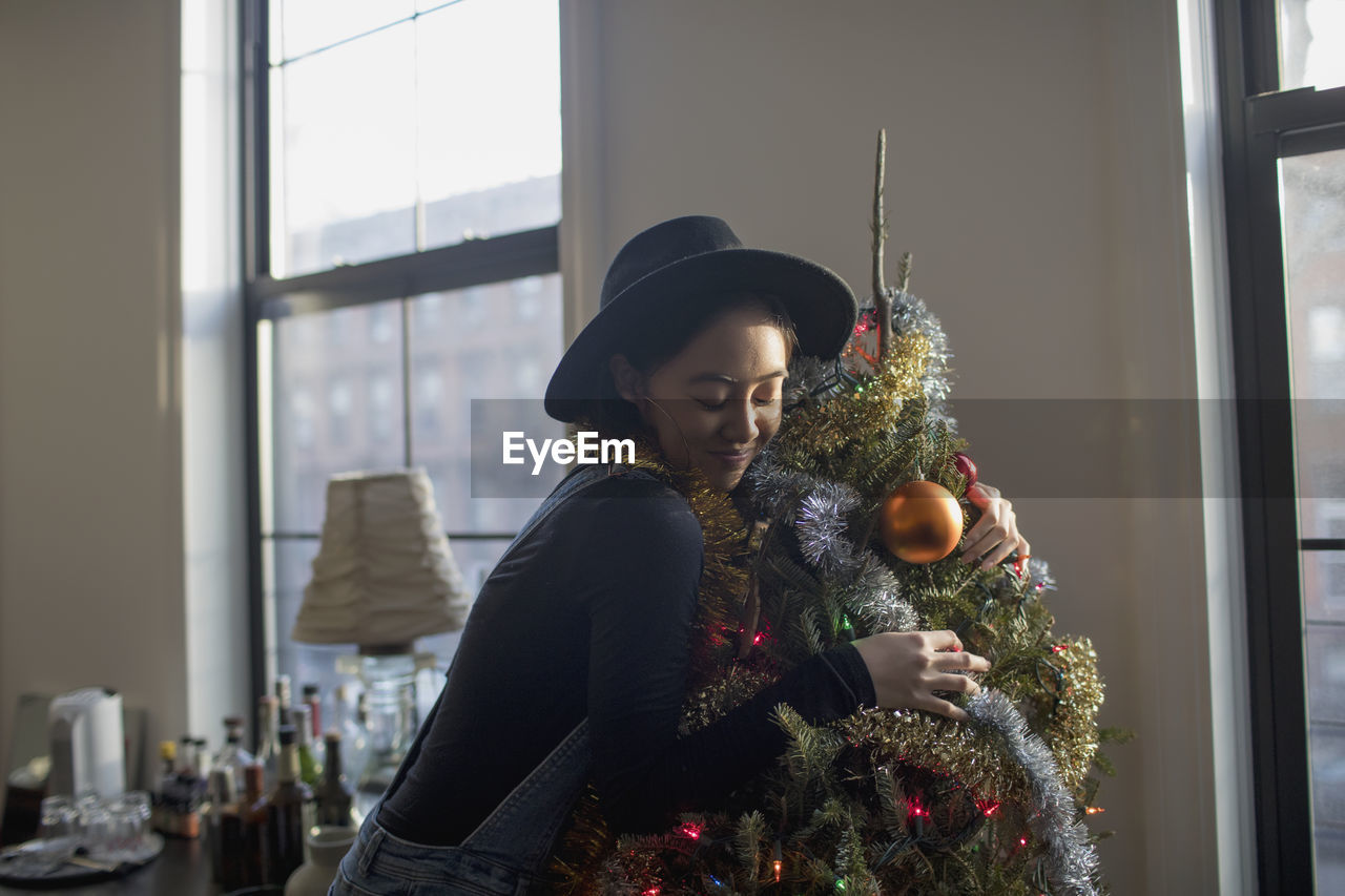 A young woman hugging a christmas tree
