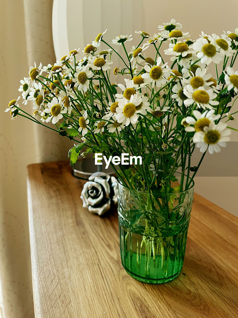 CLOSE-UP OF FLOWER VASE ON TABLE AGAINST WHITE WALL