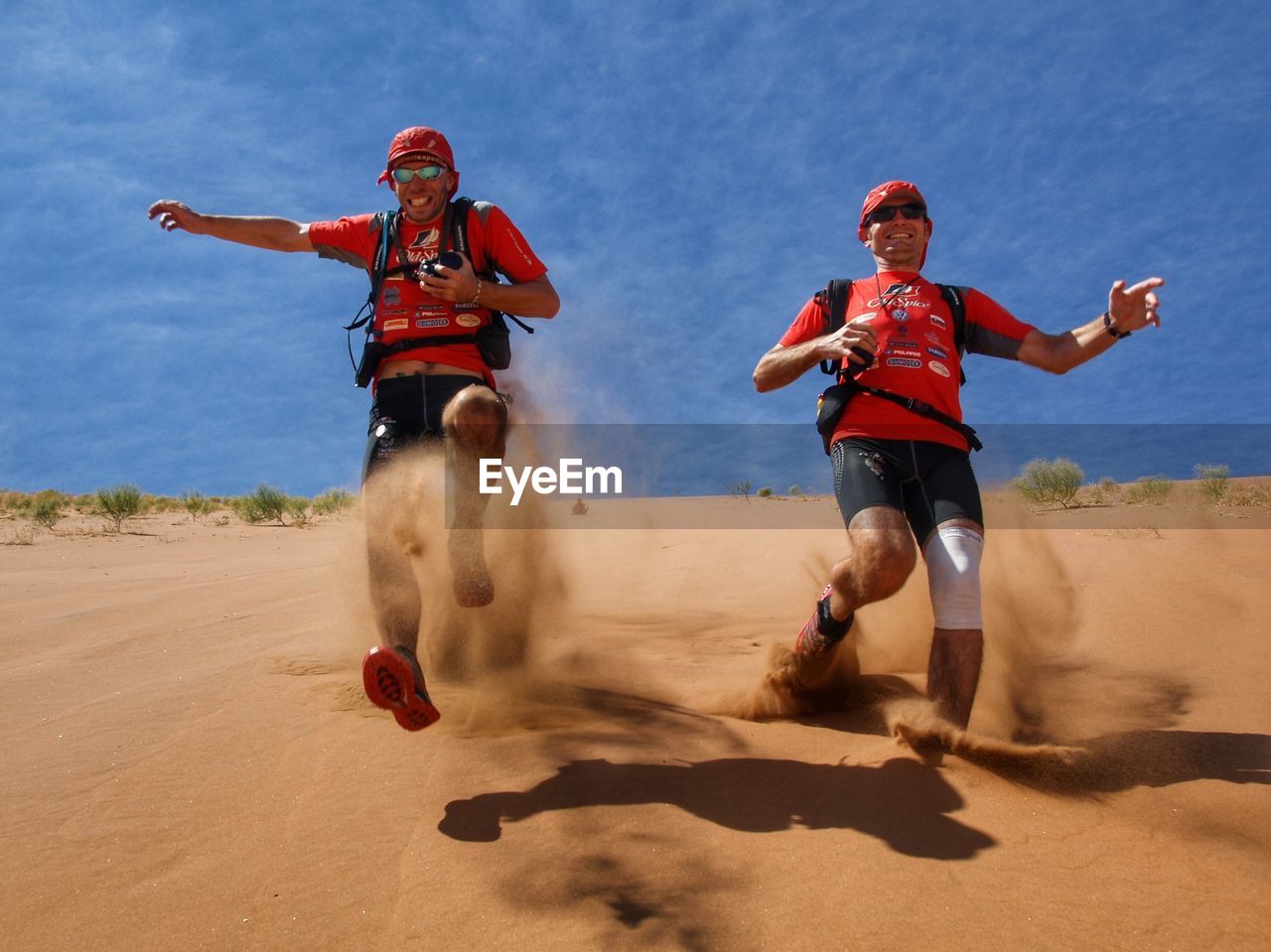 PEOPLE RUNNING ON SAND DUNE IN DESERT
