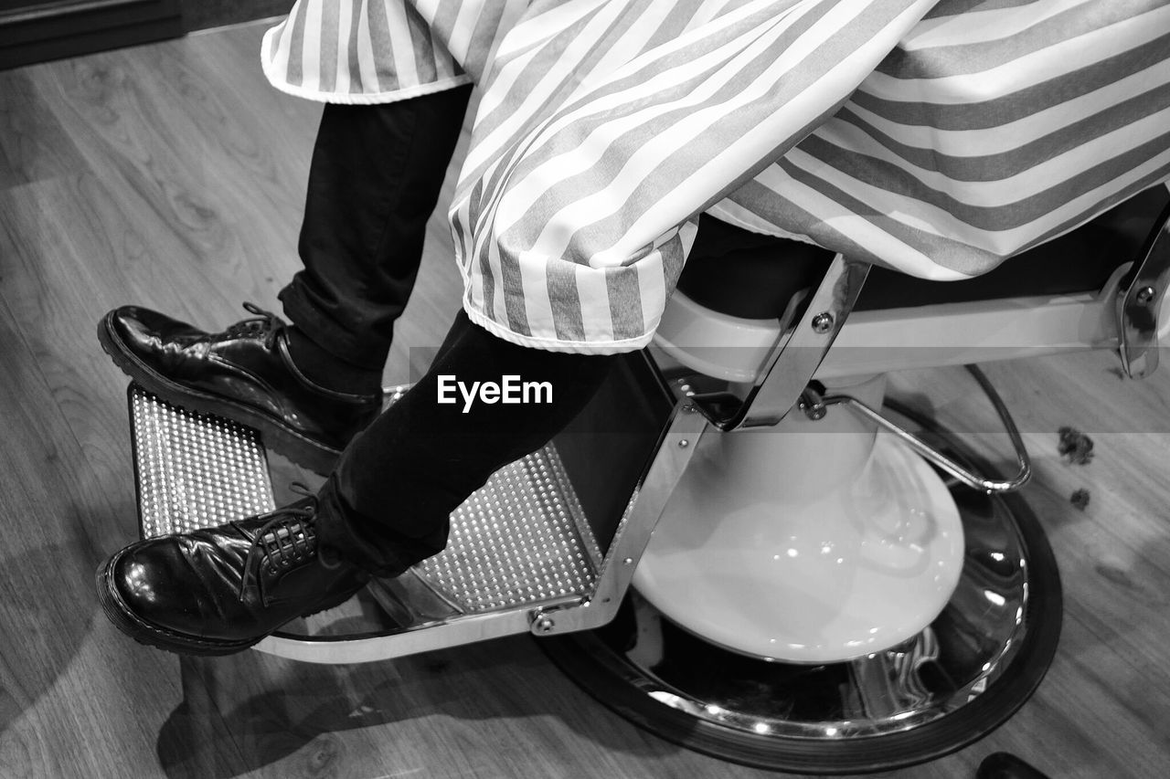 Low section of man sitting on chair in salon