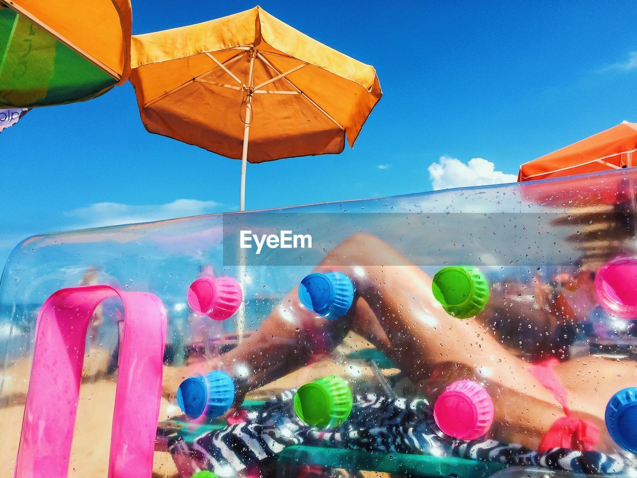 Low section of woman resting at beach seen through inflatable during sunny day