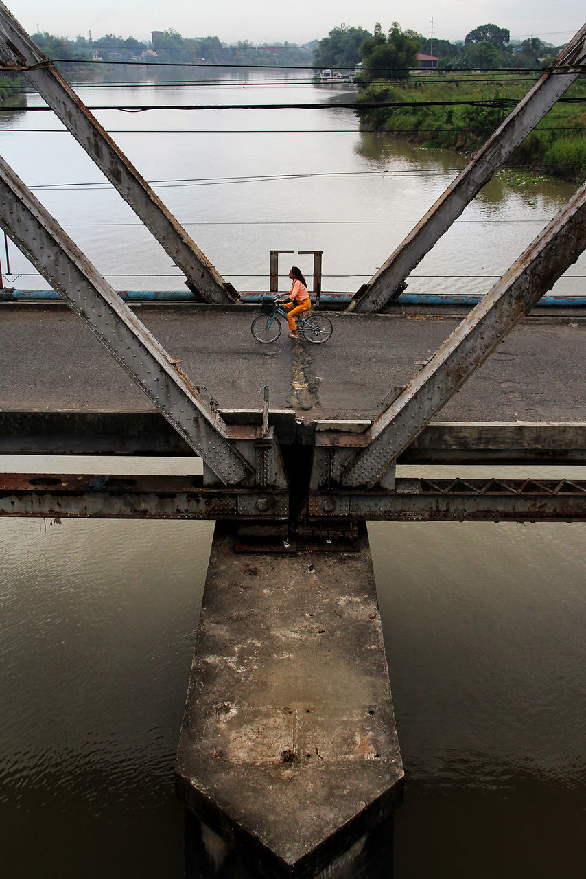 High angle view of man riding bicycle on bridge road over river