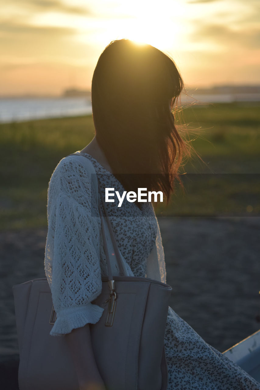 Rear view of woman  against sky during sunset
