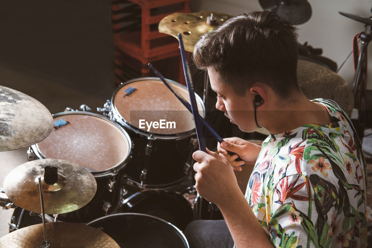 Teenager boy drummer playing on rehearsal in a studio. rock musician male teen performing a song. 