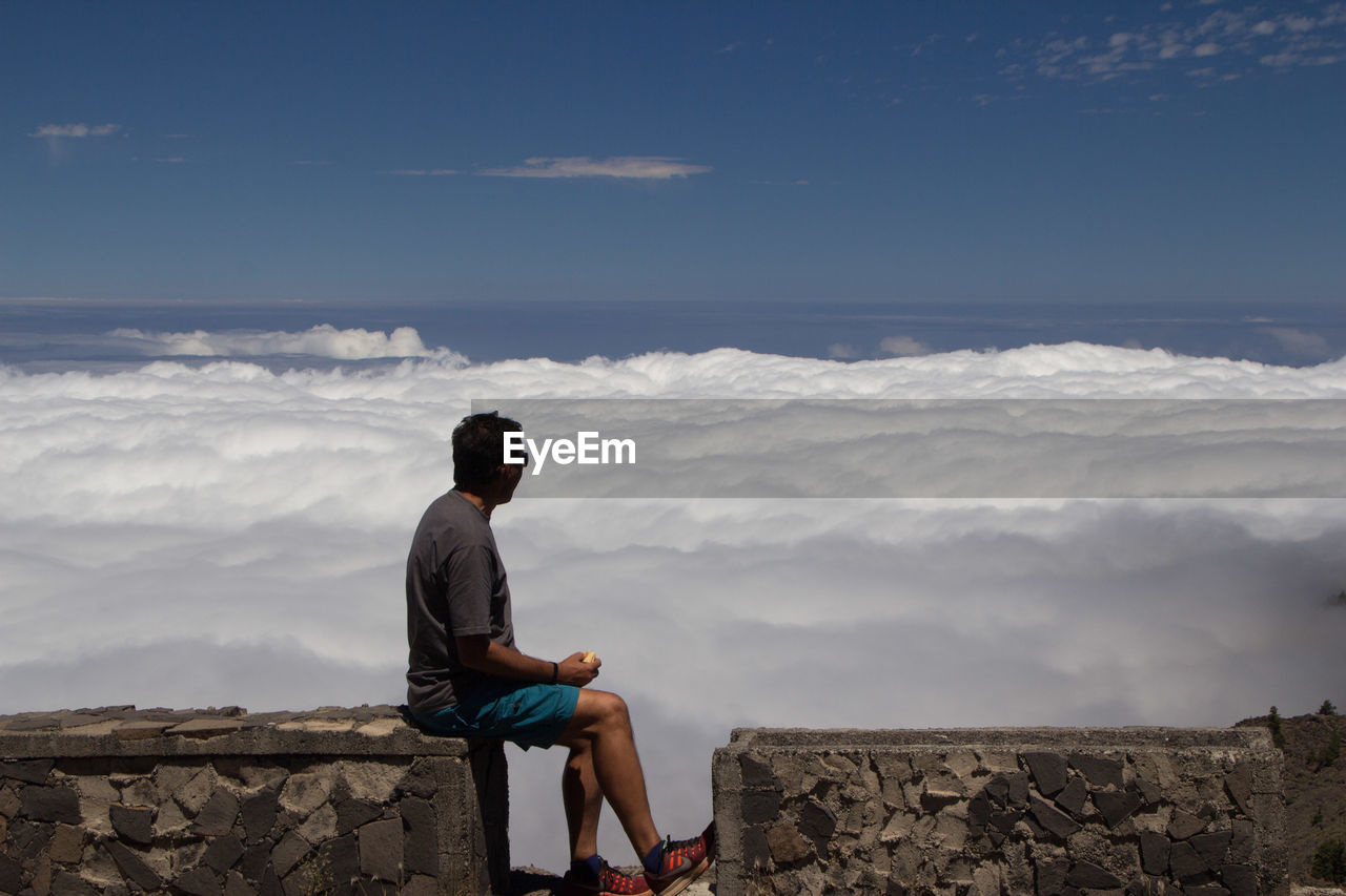 Man sitting on mountain watching the sea of clouds below him