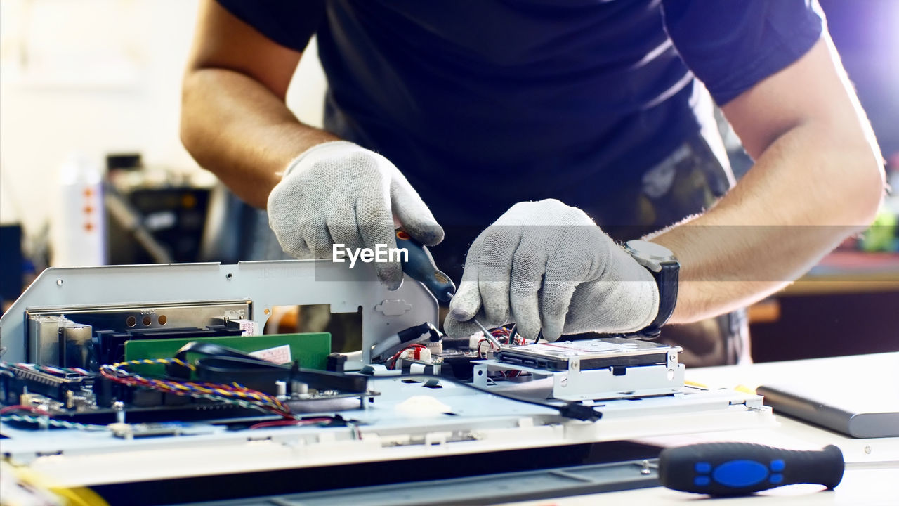 Midsection of man repairing computer equipment on table