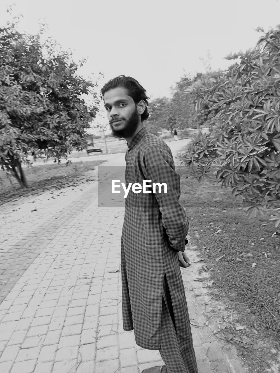 black and white, one person, young adult, monochrome photography, monochrome, white, adult, standing, black, lifestyles, plant, clothing, nature, tree, casual clothing, photo shoot, portrait, day, fashion, leisure activity, looking at camera, spring, footpath, men, outdoors, side view, three quarter length, looking, winter, smiling, full length, person, sky, women