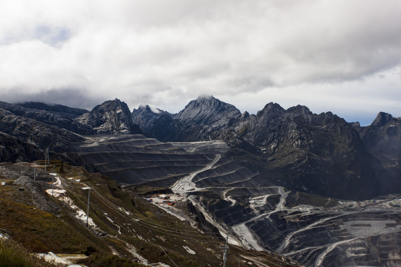 Scenic view of mountains above grasberg mine road against cloudy sky