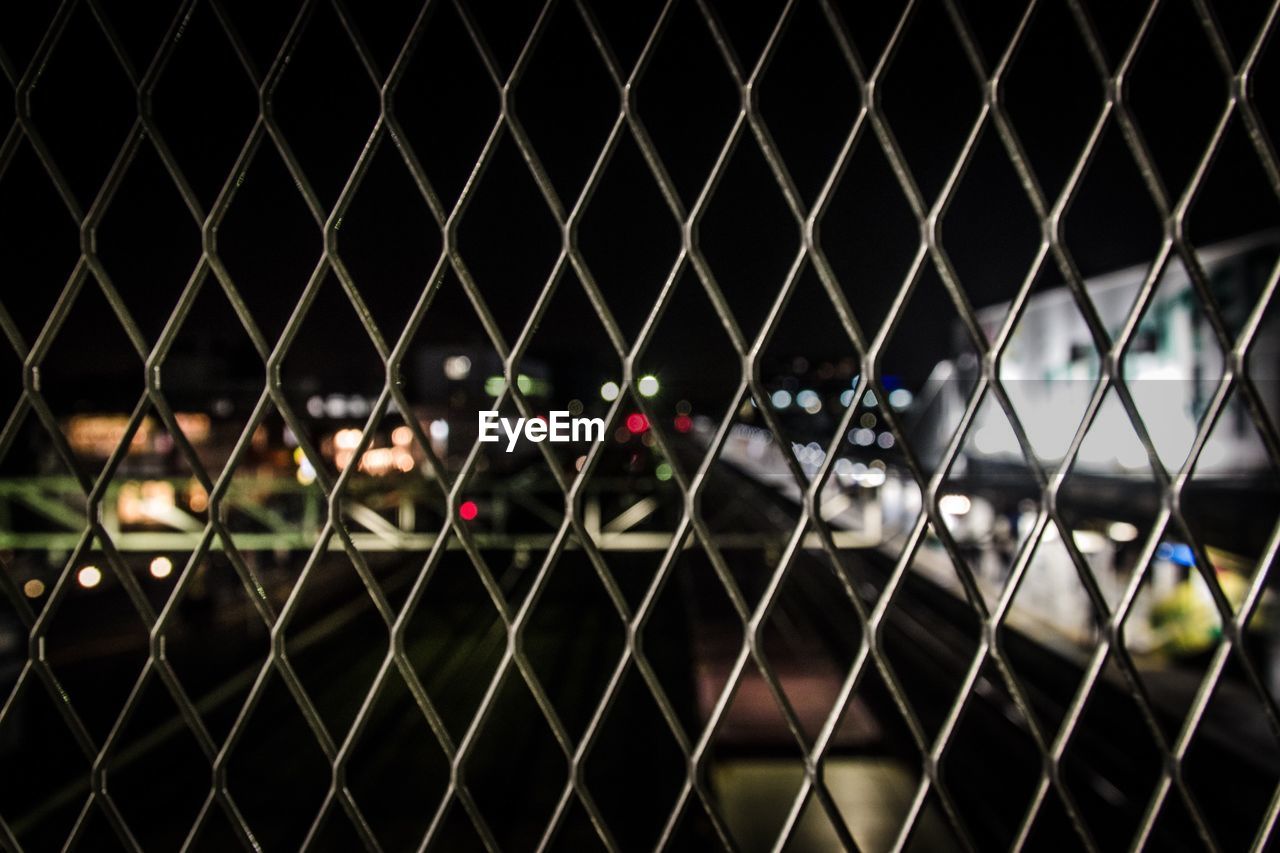 View of street seen through chainlink fence at night