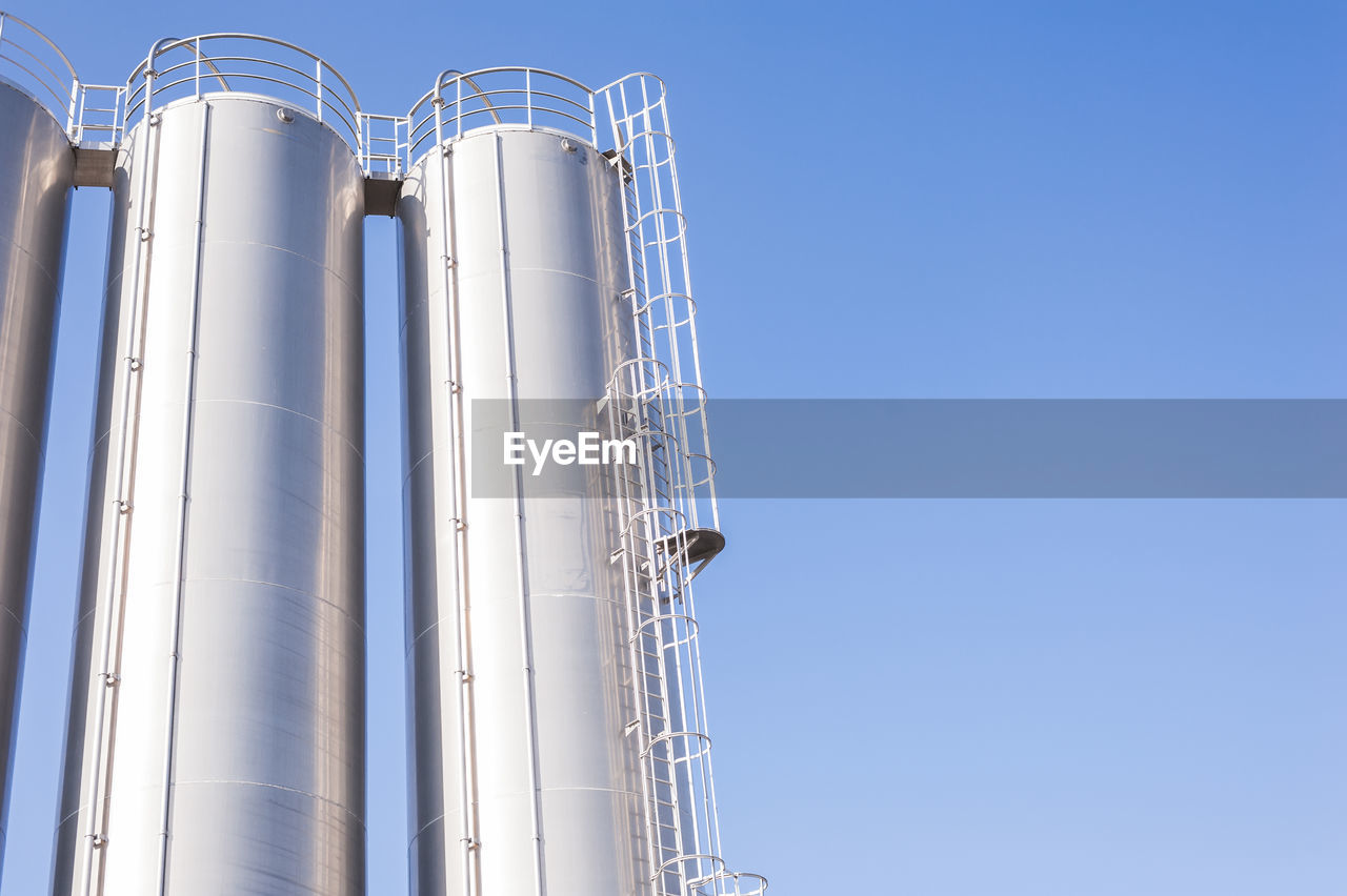 Low angle view of storage tanks against clear sky