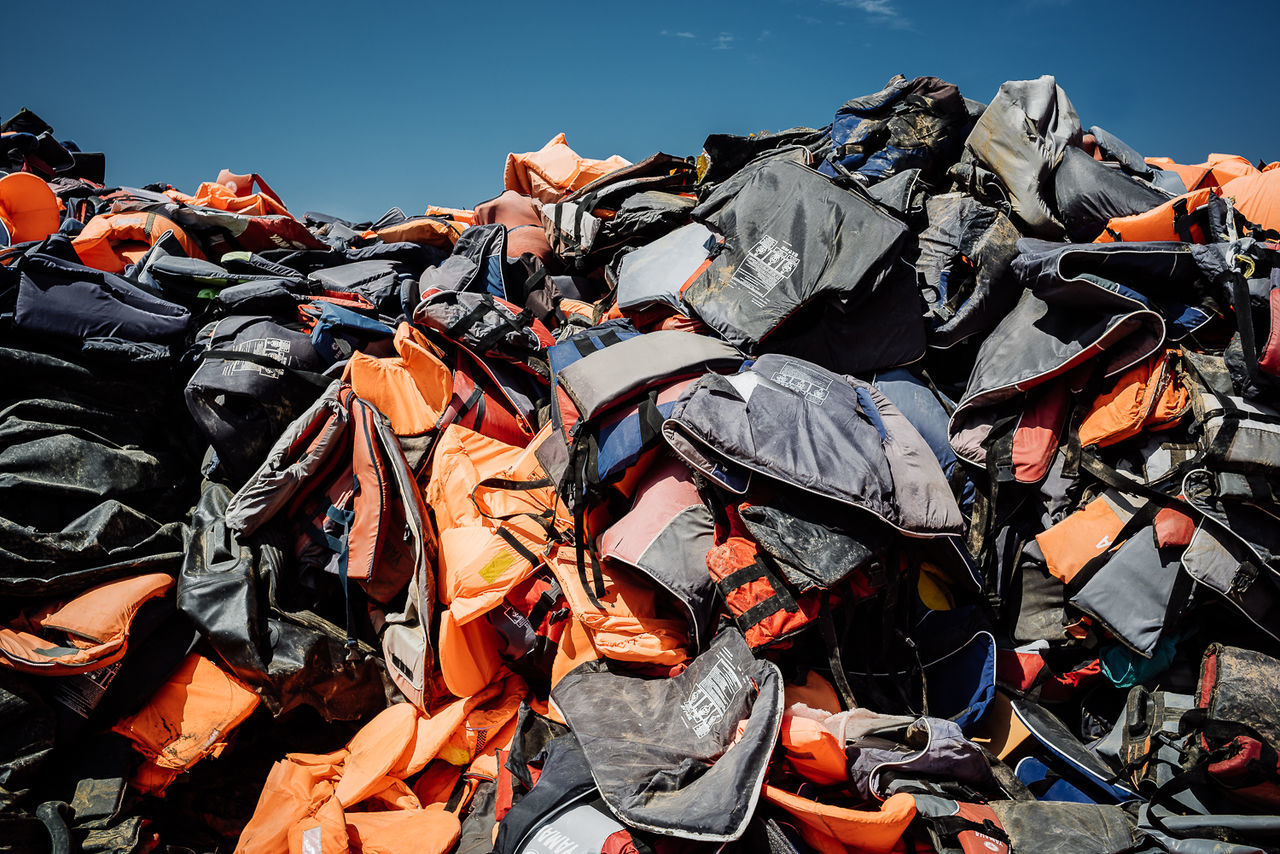 Heap of abandoned life jackets against sky