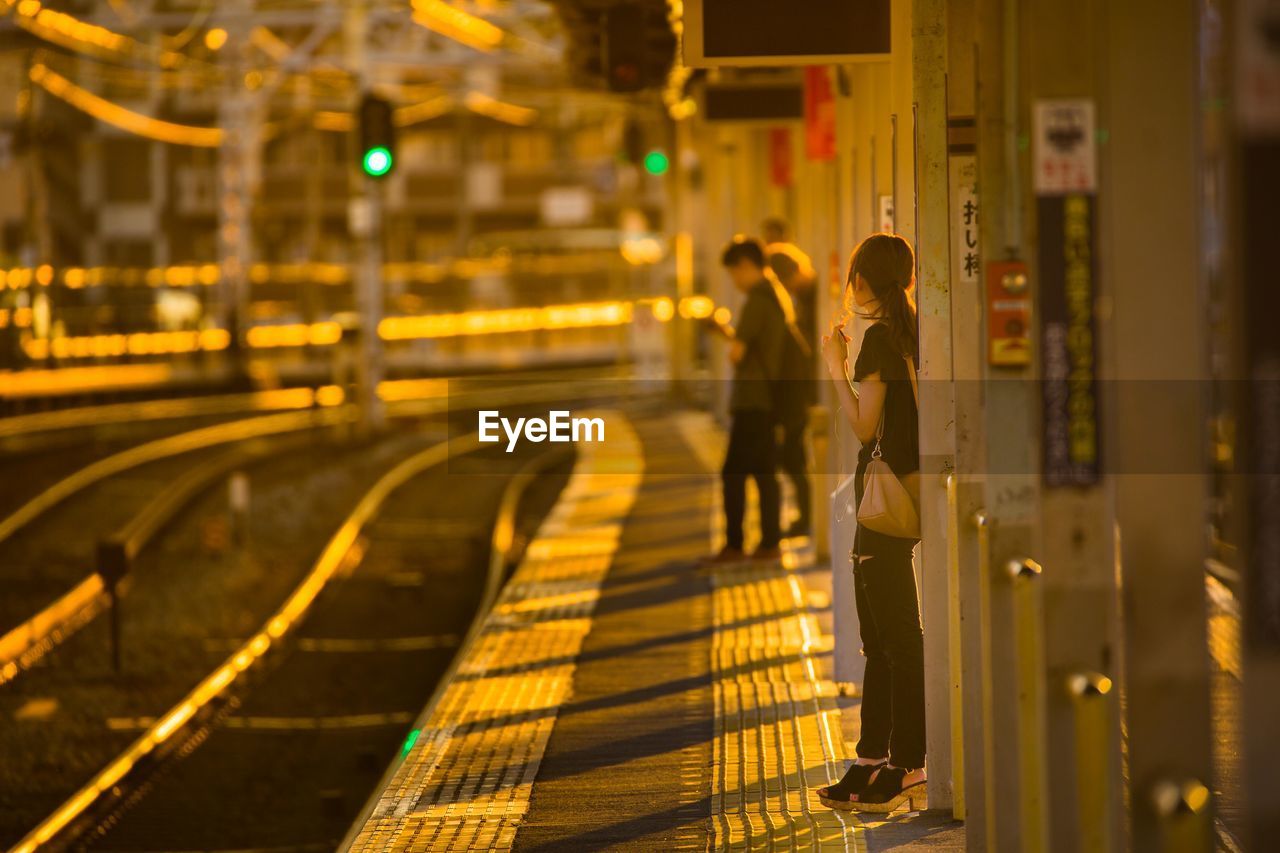People standing on railroad station at night