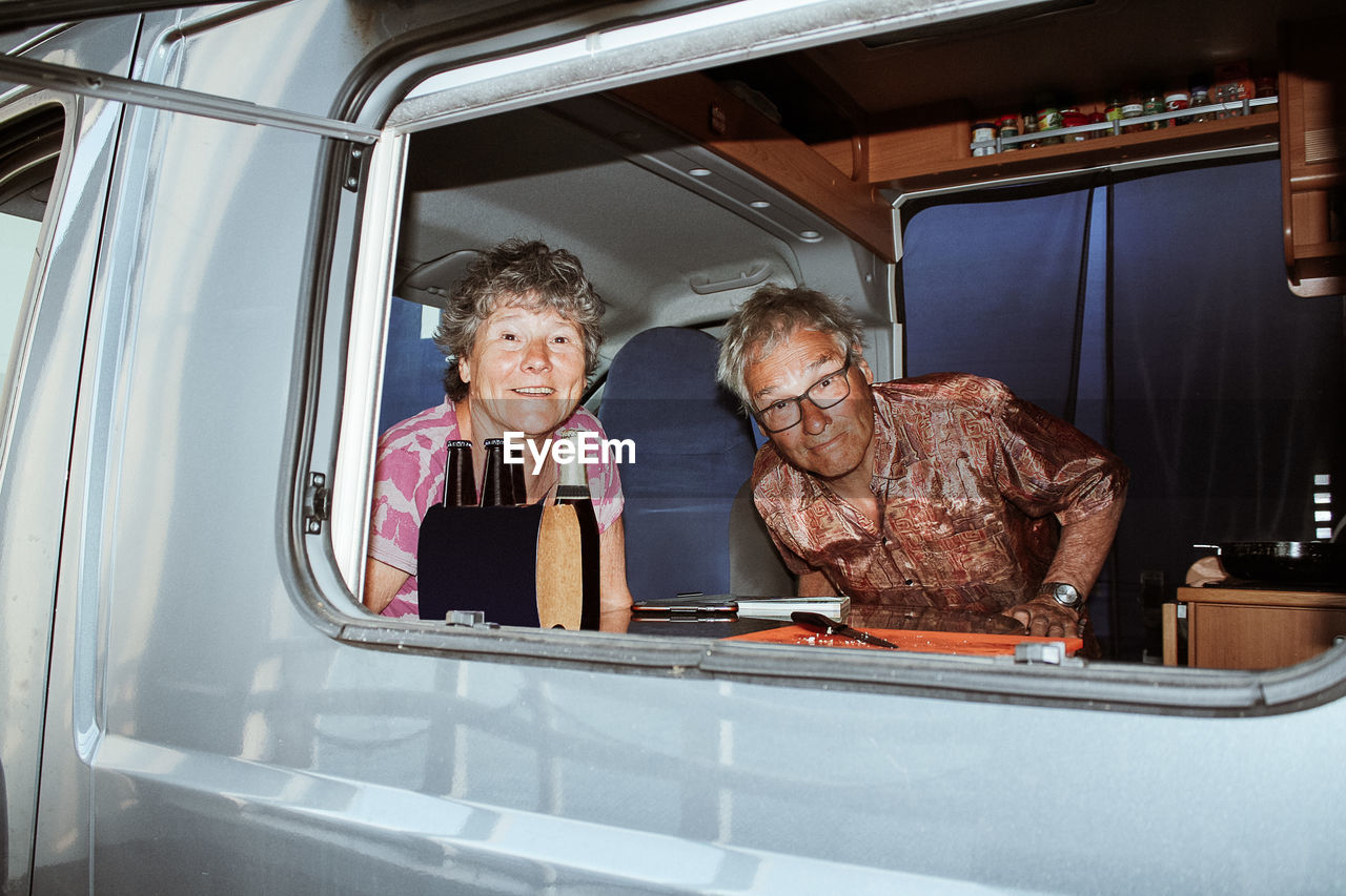 Portrait of senior couple in motor home seen through window
