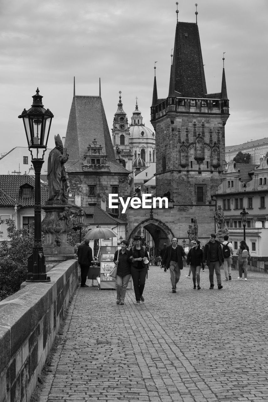 architecture, built structure, building exterior, city, travel destinations, group of people, building, history, the past, sky, place of worship, tower, religion, travel, street, tourism, belief, men, town, nature, adult, crowd, women, black and white, monochrome, landmark, lifestyles, spirituality, large group of people, walking, spire, monochrome photography, cityscape, outdoors, road, city life, cloud, tourist, worship, old, day, temple