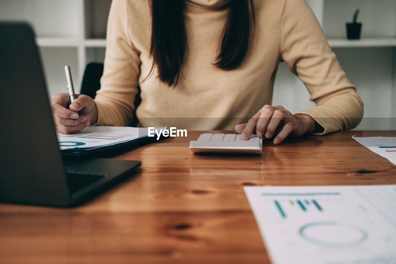 Midsection of businesswoman working on table