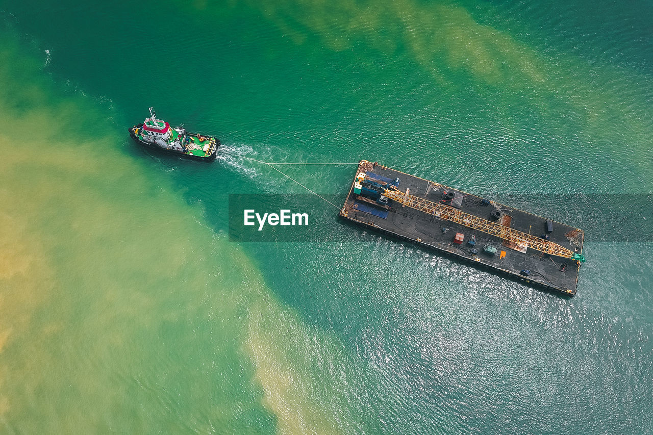Aerial view of tugboat hauling ship in sea