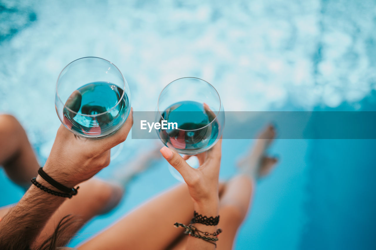 Drinking wine by the pool.two glasses of blue wine.