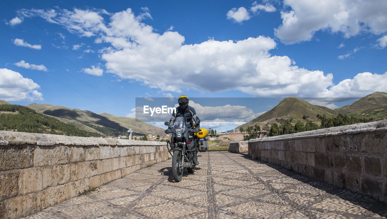 Motorbike driving over a bridge of the urubamba river, cusco, peru