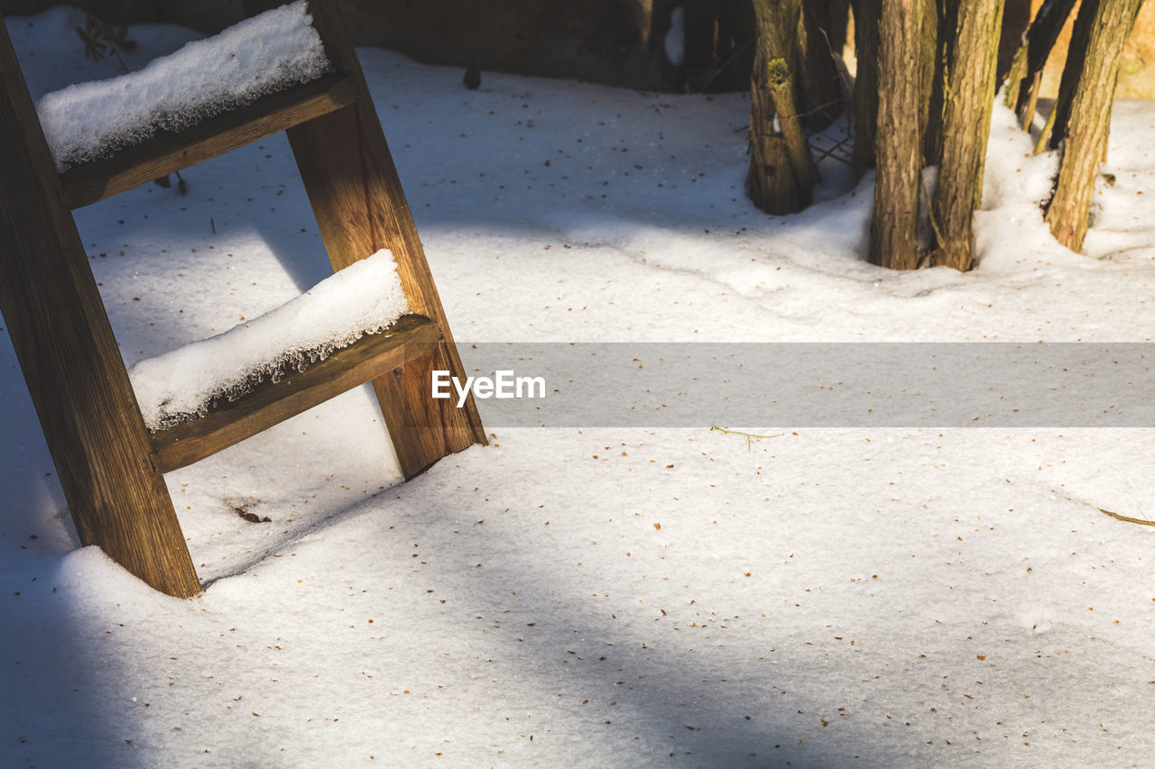 HIGH ANGLE VIEW OF EMPTY CHAIR ON SNOWY FIELD