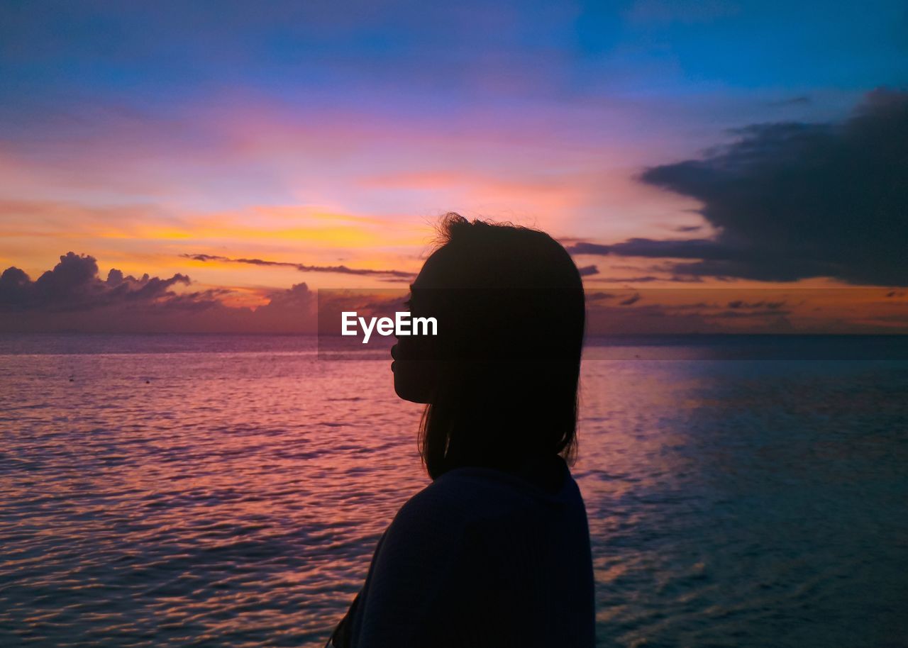 View of woman looking at sea against sky during sunset