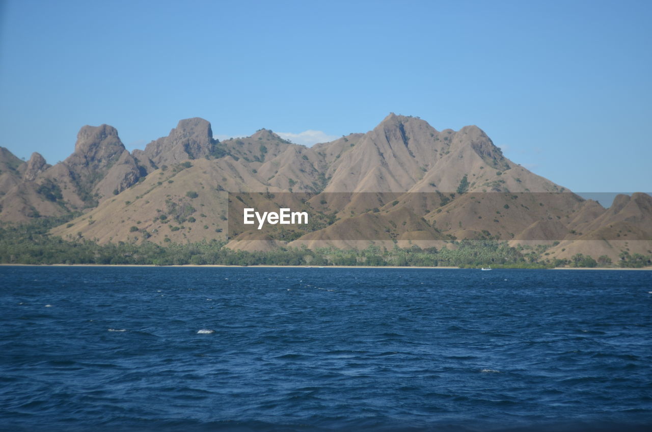SCENIC VIEW OF SEA AND MOUNTAIN AGAINST CLEAR BLUE SKY