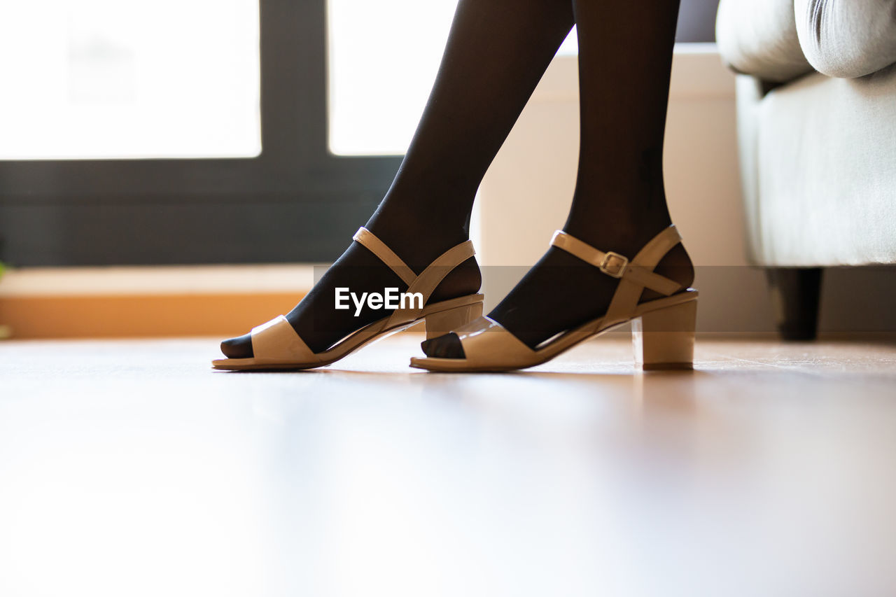low section of woman standing on hardwood floor at home