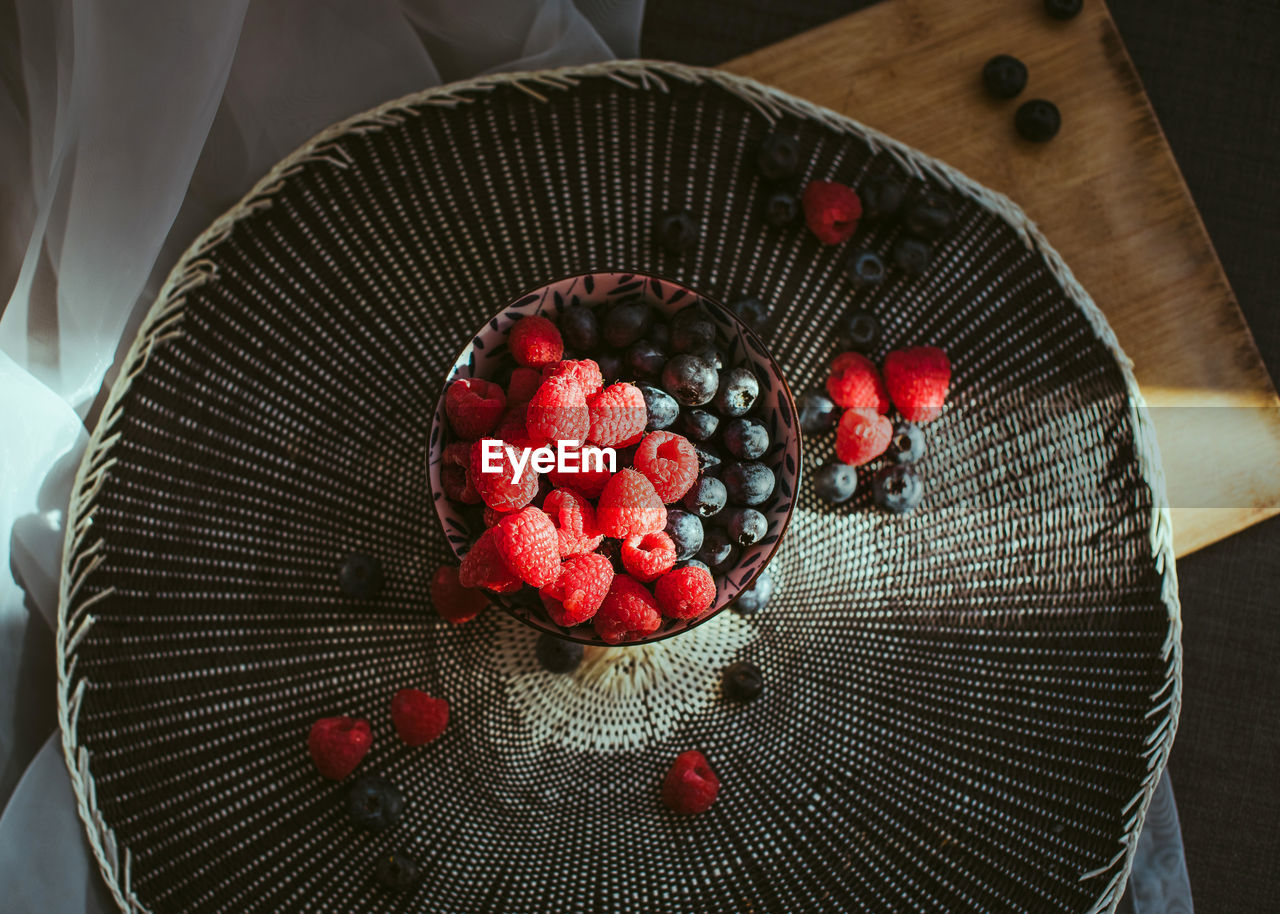Little bowl with raspberries and blueberries, in a nice background.