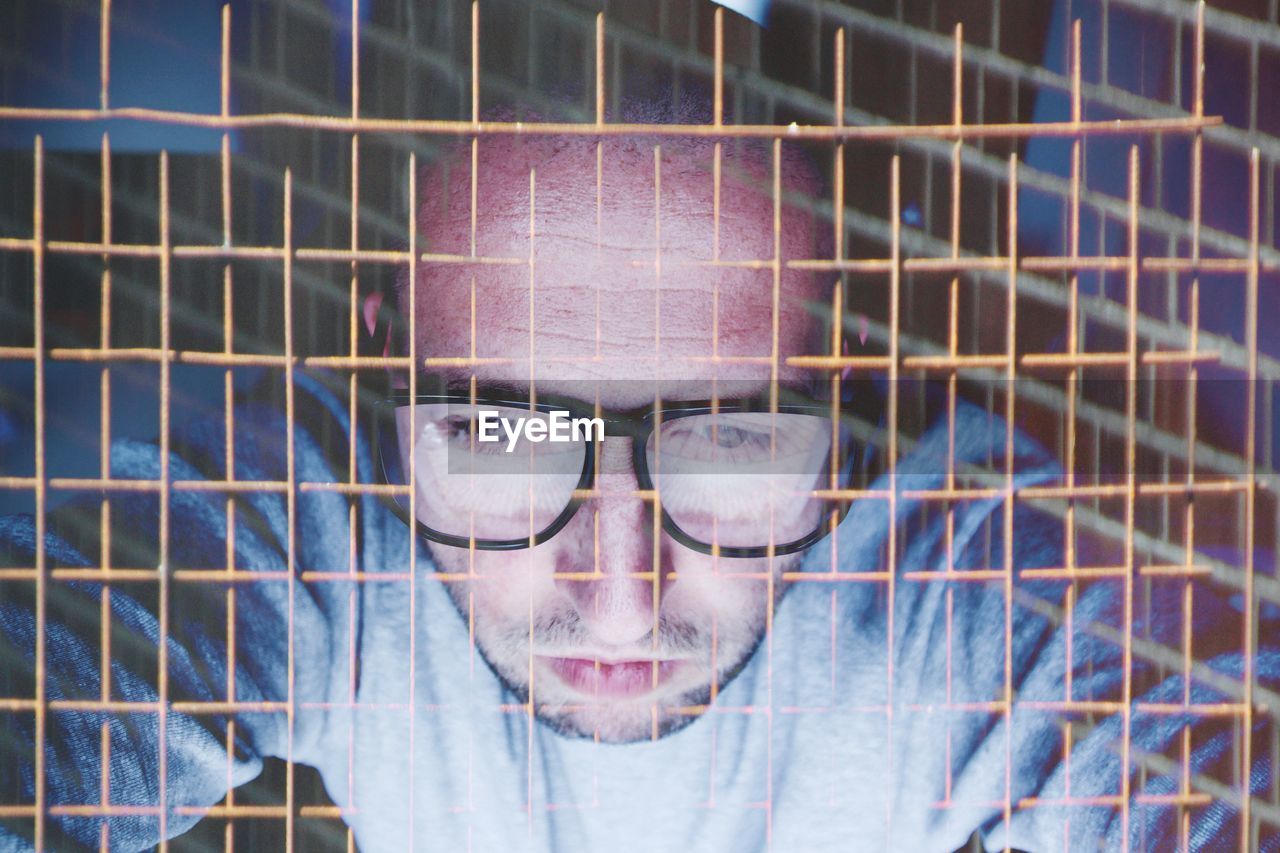 Double exposure of mid adult man with metal fence