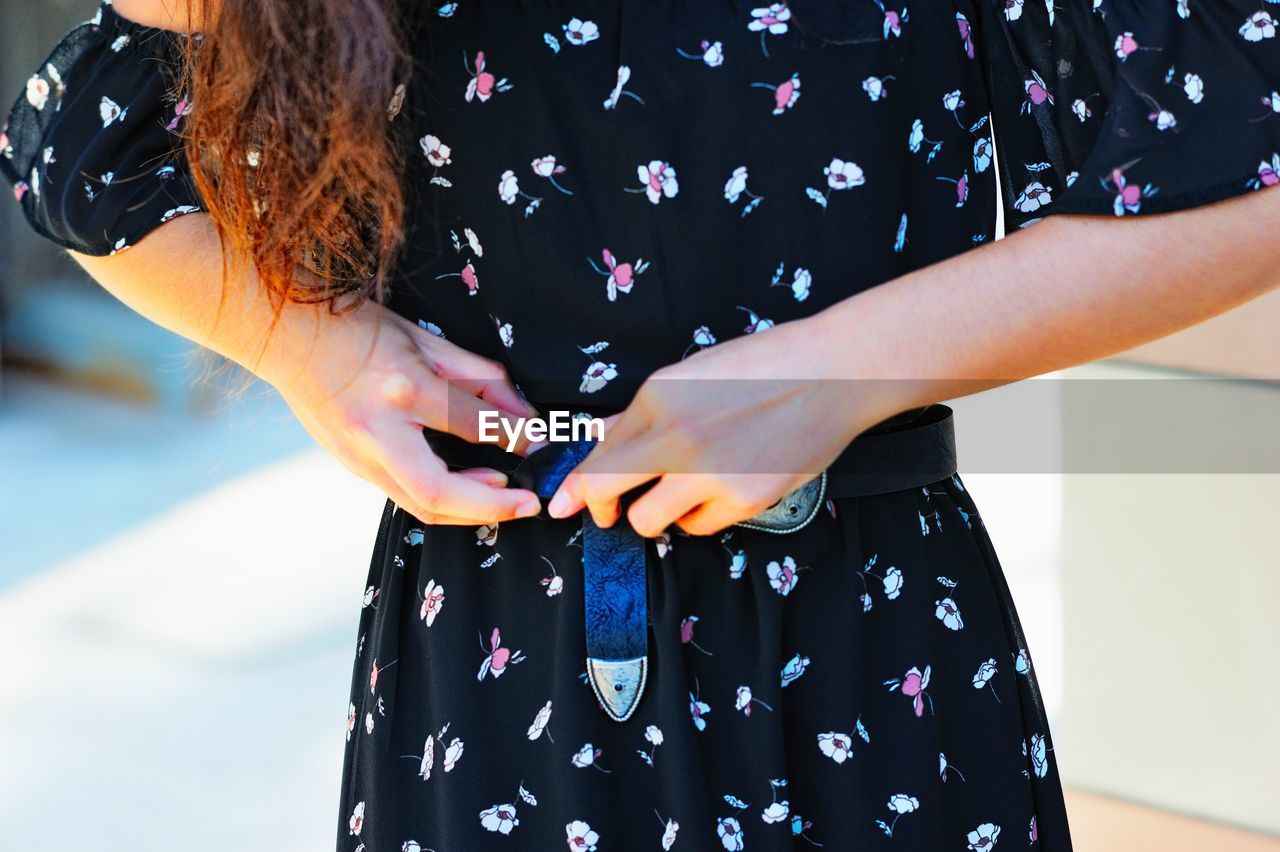 Midsection of woman adjusting dress