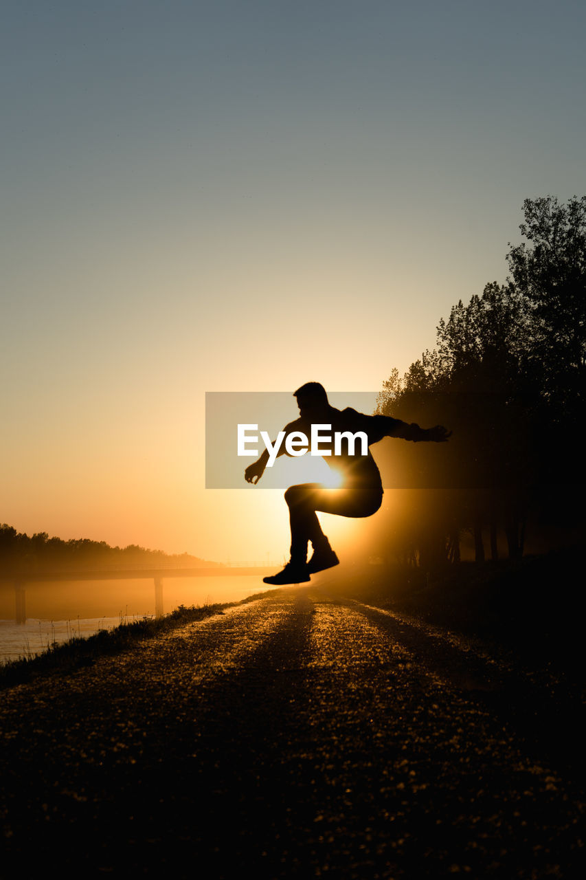 Silhouette man jumping against clear sky during sunset