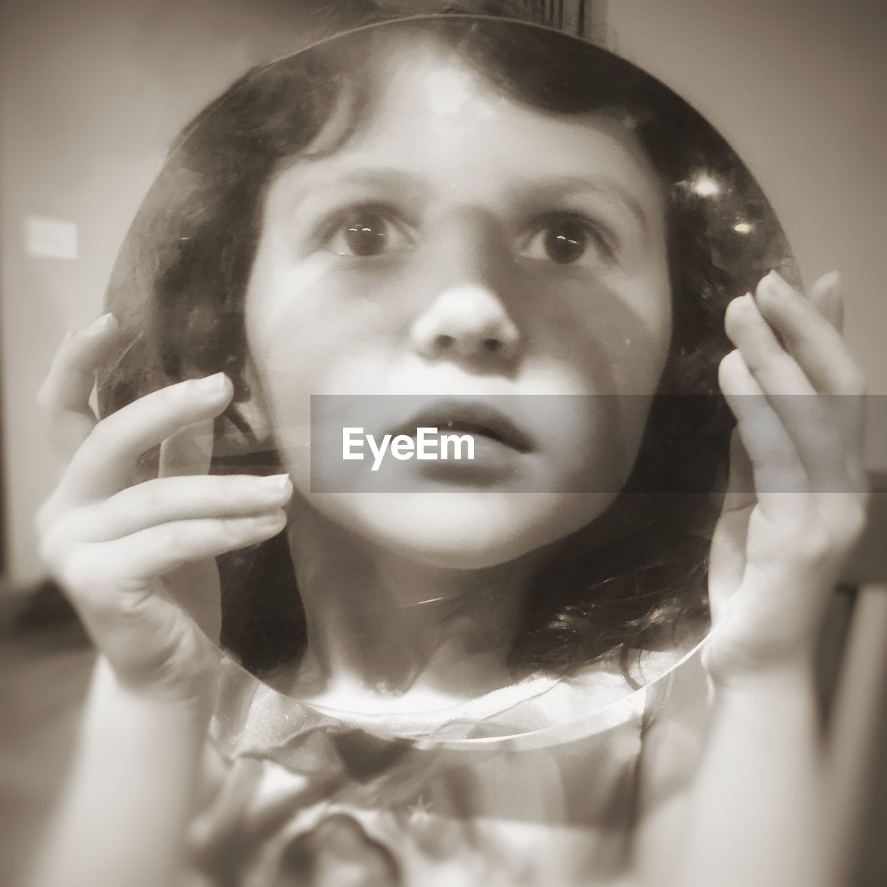 Close-up of girl holding circle shaped transparent glass