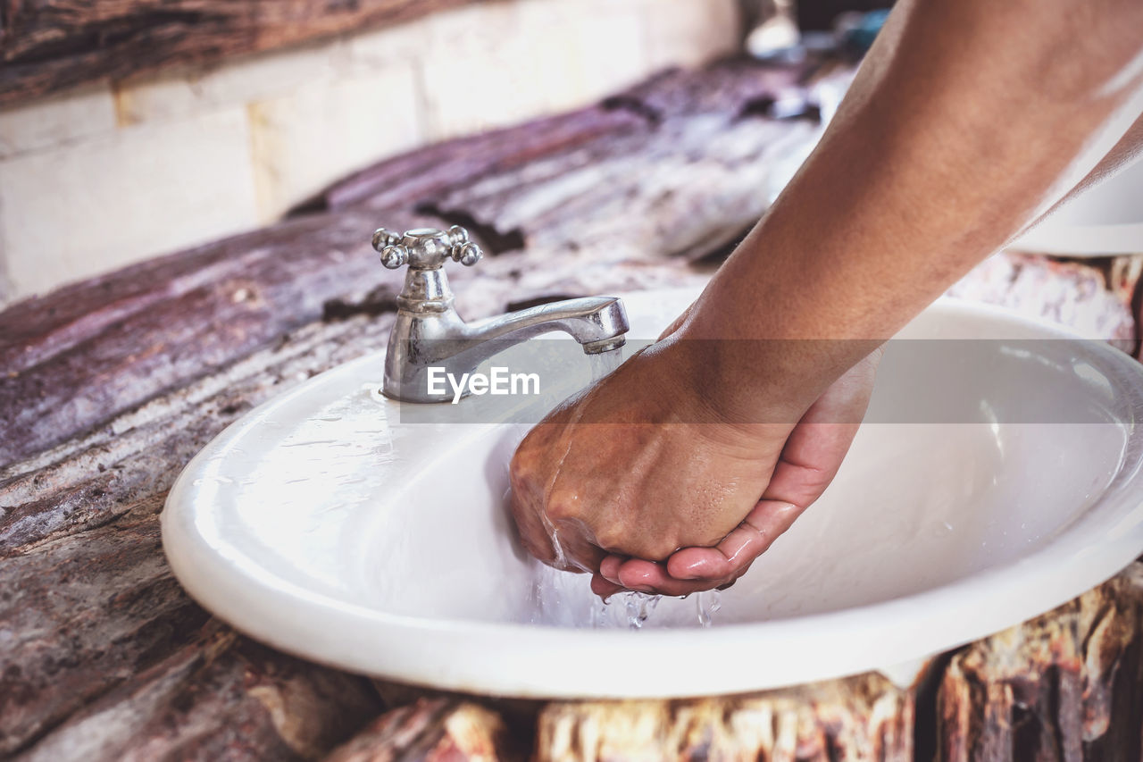 Person washing hands at faucet